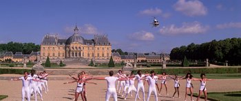 Movie still from “Moonraker” (1979), directed by Lewis Gilbert – A group of people in white clothes and a helicopter flying in the sky; Extreme Wide shot, High angle