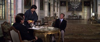 Movie still from “Moonraker” (1979), directed by Lewis Gilbert – A man sitting at a table in a living room; Medium shot, High angle