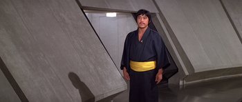 Movie still from “Moonraker” (1979), directed by Lewis Gilbert – A man wearing a black robe and yellow belt; Medium shot, Low angle