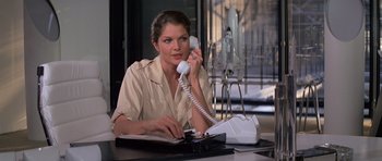 Movie still from “Moonraker” (1979), directed by Lewis Gilbert – A woman sitting at a desk talking on a phone; Medium shot, Low angle