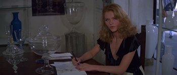 Movie still from “Moonraker” (1979), directed by Lewis Gilbert – A woman sitting at a table writing on a piece of paper; Medium shot, Over the shoulder angle