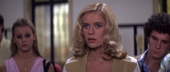 Movie still from “Moonraker” (1979), directed by Lewis Gilbert – A woman with blonde curly hair wearing a white shirt; Close Up shot, Over the shoulder angle