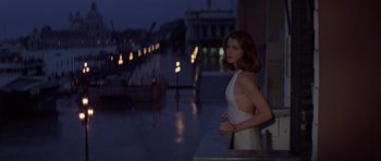 Movie still from “Moonraker” (1979), directed by Lewis Gilbert – A woman in a white dress standing on a balcony; Medium shot, Low angle