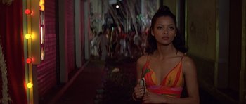 Movie still from “Moonraker” (1979), directed by Lewis Gilbert – A beautiful woman in a colorful dress holding a cell phone; Medium shot, Low angle