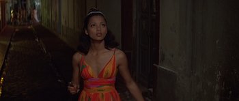 Movie still from “Moonraker” (1979), directed by Lewis Gilbert – A woman in a colorful dress holding a cell phone; Medium shot, Low angle