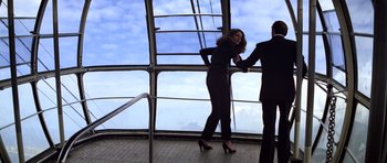 Movie still from “Moonraker” (1979), directed by Lewis Gilbert – A man and a woman standing next to each other in front of a window; Wide shot, Low angle