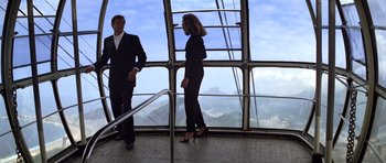 Movie still from “Moonraker” (1979), directed by Lewis Gilbert – A man and a woman standing next to each other in front of a window; Wide shot, Low angle