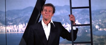 Movie still from “Moonraker” (1979), directed by Lewis Gilbert – A man wearing a suit and tie holding a ladder; Medium shot, Low angle