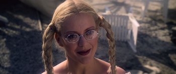 Movie still from “Moonraker” (1979), directed by Lewis Gilbert – A woman wearing glasses and pigtails is smiling for the camera; Close Up shot, Over the shoulder angle