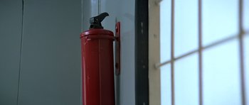 Movie still from “Moonraker” (1979), directed by Lewis Gilbert – A red fire extinguisher hanging on the side of a wall; Extreme Close Up shot, Low angle