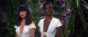 Movie still from “Moonraker” (1979), directed by Lewis Gilbert – Two women standing next to each other wearing white and yellow; Close Up shot, Low angle