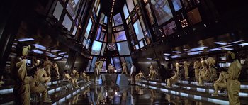 Movie still from “Moonraker” (1979), directed by Lewis Gilbert – A group of people sitting in a room with many windows; Extreme Wide shot, High angle