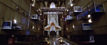 Movie still from “Moonraker” (1979), directed by Lewis Gilbert – An airplane in a hangar with people standing around it; Extreme Wide shot, Low angle