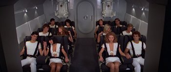 Movie still from “Moonraker” (1979), directed by Lewis Gilbert – A group of people sitting on a plane; Wide shot, High angle