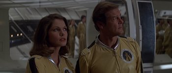 Movie still from “Moonraker” (1979), directed by Lewis Gilbert – A man and a woman standing next to each other; Medium shot, Low angle