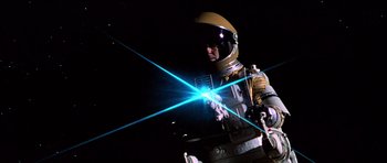 Movie still from “Moonraker” (1979), directed by Lewis Gilbert – A person in a spacesuit and helmet holding a laser beam; Medium shot, Low angle