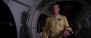 Movie still from “Moonraker” (1979), directed by Lewis Gilbert – A man in a yellow suit standing next to an airplane; Medium shot, Low angle