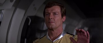 Movie still from “Moonraker” (1979), directed by Lewis Gilbert – A man that is wearing a yellow and silver shirt; Close Up shot, Low angle