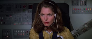 Movie still from “Moonraker” (1979), directed by Lewis Gilbert – A woman in a yellow jacket with headphones on; Close Up shot, Low angle