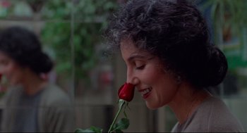 Movie still from “Moonstruck” (1987), directed by Norman Jewison – A woman holding a red rose up to her face; Close Up shot, Over the shoulder angle