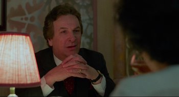 Movie still from “Moonstruck” (1987), directed by Norman Jewison – A man in a suit and tie sitting at a table; Close Up shot, Over the shoulder angle