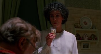 Movie still from “Moonstruck” (1987), directed by Norman Jewison – A woman holding a glass of champagne in front of a mirror; Close Up shot, Over the shoulder angle