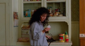 Movie still from “Moonstruck” (1987), directed by Norman Jewison – A woman in a kitchen looking at a receipt; Medium shot, Low angle