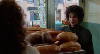 Movie still from “Moonstruck” (1987), directed by Norman Jewison – A woman sitting in front of a bunch of bagels; Medium shot, Over the shoulder angle