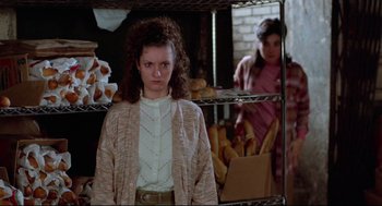 Movie still from “Moonstruck” (1987), directed by Norman Jewison – A woman standing next to a rack of bread; Medium shot, Over the shoulder angle