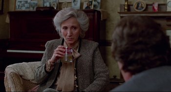 Movie still from “Moonstruck” (1987), directed by Norman Jewison – An older woman holding a glass in her hand; Medium shot, Over the shoulder angle
