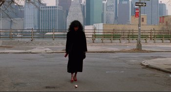 Movie still from “Moonstruck” (1987), directed by Norman Jewison – A woman in a long black coat and red shoes walking across a street; Wide shot, High angle