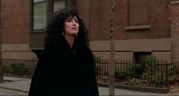 Movie still from “Moonstruck” (1987), directed by Norman Jewison – A woman in a long black coat standing on the sidewalk; Close Up shot, High angle