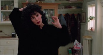 Movie still from “Moonstruck” (1987), directed by Norman Jewison – A woman in a black coat is posing for a picture; Medium shot, High angle
