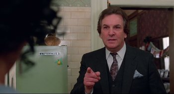Movie still from “Moonstruck” (1987), directed by Norman Jewison – A man wearing a suit and tie in front of a refrigerator; Close Up shot, Low angle