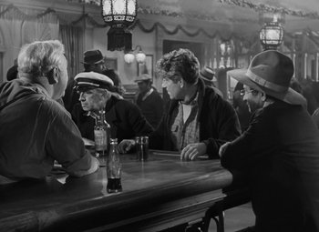 Movie still from “Moontide” (1942), directed by Fritz Lang – A black and white photo of people sitting at a bar; Medium shot, Over the shoulder angle