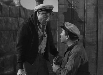 Movie still from “Moontide” (1942), directed by Fritz Lang – Two men are talking to each other in a black and white photo; Medium shot, High angle