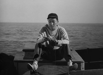 Movie still from “Moontide” (1942), directed by Fritz Lang – A black and white photo of a man sitting on a boat; Medium shot, High angle