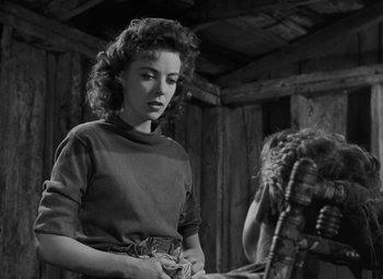 Movie still from “Moontide” (1942), directed by Fritz Lang – A woman standing in front of a wooden structure; Medium shot, Over the shoulder angle