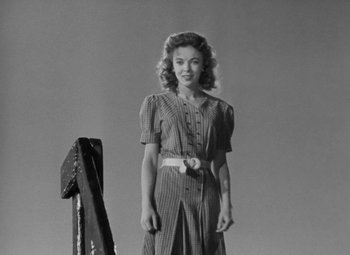Movie still from “Moontide” (1942), directed by Fritz Lang – A woman standing in front of an ironing board in front of a sky background; Medium shot, Low angle