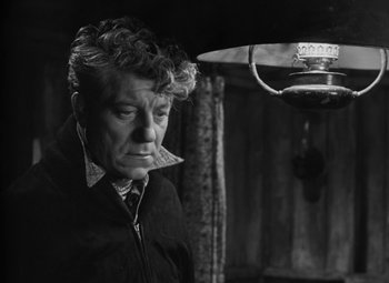 Movie still from “Moontide” (1942), directed by Fritz Lang – An older man is looking down at a lamp; Close Up shot, High angle