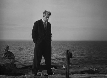 Movie still from “Moontide” (1942), directed by Fritz Lang – A black and white photo of a man standing by the ocean; Wide shot, Low angle