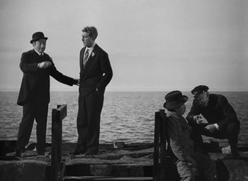 Movie still from “Moontide” (1942), directed by Fritz Lang – Two men shaking hands on a pier near the ocean; Wide shot, Over the shoulder angle