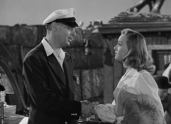 Movie still from “Moontide” (1942), directed by Fritz Lang – A man and a woman shaking hands in a black and white photo; Medium shot, Over the shoulder angle
