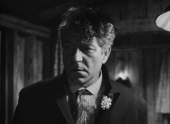 Movie still from “Moontide” (1942), directed by Fritz Lang – Black and white photograph of a man wearing a suit and tie; Close Up shot, Low angle