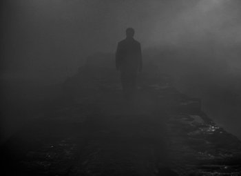Movie still from “Moontide” (1942), directed by Fritz Lang – A man standing in the middle of a road in the middle of the night; Wide shot, Low angle