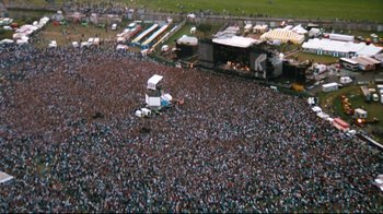 Movie still from “Moonwalker” (1988), directed by Jerry Kramer – An aerial view of a crowd of people at an outdoor concert; Extreme Wide shot, High angle