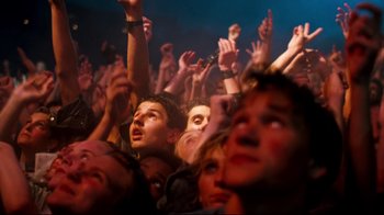 Movie still from “Moonwalker” (1988), directed by Jerry Kramer – A group of people that are sitting in a crowd; Medium shot, High angle