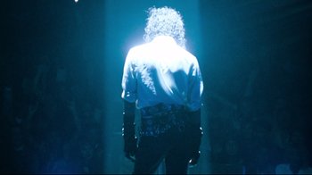 Movie still from “Moonwalker” (1988), directed by Jerry Kramer – A man standing in the middle of a stage; Medium shot, Low angle