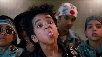 Movie still from “Moonwalker” (1988), directed by Jerry Kramer – A young man sticking out his tongue while wearing a bandana; Close Up shot, High angle