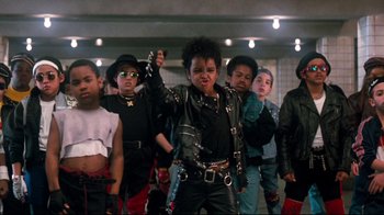 Movie still from “Moonwalker” (1988), directed by Jerry Kramer – A group of young men standing next to each other in a room; Medium shot, High angle